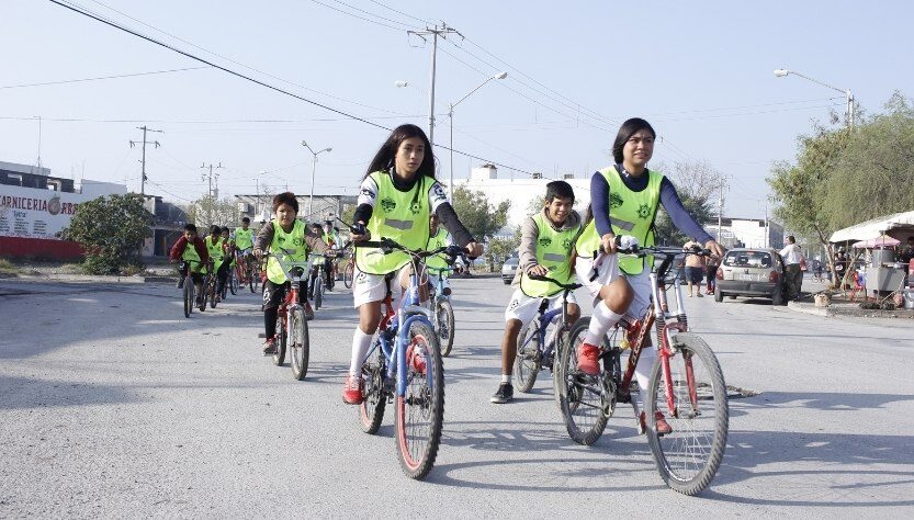 Futbol y bicicletas, niñas ruedan en sus bicicletas hacia el campo de futbol
