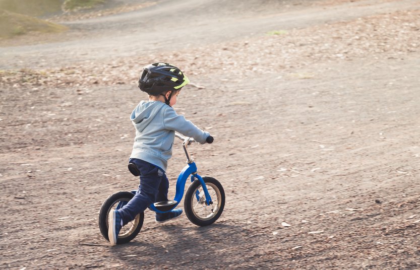 Niño con casco anda sobre su bicicleta de balance
